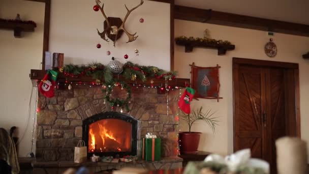 Quemadura de fuego en una chimenea decorada con luces de guirnalda, corona, medias y cajas de regalo en la víspera de Navidad. Celebración de fiestas de Año Nuevo. Dolly tiro 1080p Full HD . — Vídeo de stock