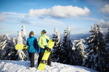 İki snowboard kayak merkezi poz. Ormanı backcountry freeride için onların snowboards taşıyan ve yansıtıcı gözlük, renkli moda kıyafet giyen binici arkadaşlar. Boşaltmak alan.