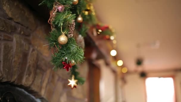 Bearded man in kniited sweater and hat hanging Christmas stocking or sock above fireplace decorated with colorful flashing garland lights and wreath. New Year holidays preparation and decoration. — Stock Video