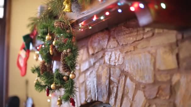 Warme gezellige stenen open haard versierd voor de kerst met krans, kousen, garland lichten. Schoorsteenmantel met decoraties voor Nieuwjaar vakantie. Feestelijke authentiek interieur. Dolly schot. — Stockvideo