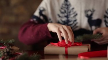 Şömine, kutular, çam dalları, koni ile dekorasyon sarma yakınındaki bir hediyeler Noel için bir yay bağlama eller yakın görünümünü mans, baston şekerler sunan gösteren tablo üzerinde kamera için sunar.