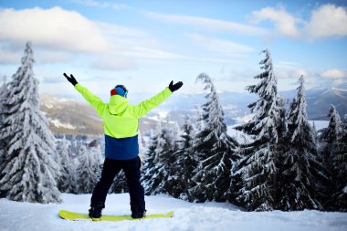 Snowboard kaldırdı kollarını ve ellerini gökyüzüne Kayak Merkezi için. Adam dağın tepesinde ormanı backcountry freeride güzel manzara zevk için çıktı. Rapture, özgürlük ve zafer an.