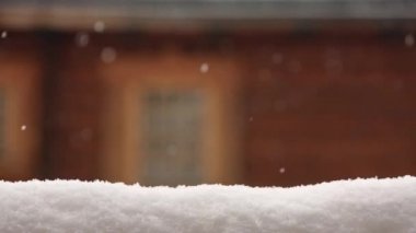 Kar yüzeyi ürün yerleştirme için kaplı. Pencere arka plan üzerinde bulanık ahşap evin duvar. Kış gününde yoğun kar yağışı. Noel evi ve boşaltmak alan ile arka plan. Büyük kar taneleri.