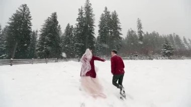 Genç gelin damat onu takip etmek ve yoğun kar yağışı altında rancho eğlenin soran orman için çalıştırıyor. Kış düğün ilham ve peri masalı. Ay tatlım ve kavram beni takip edin. Ağır çekim.
