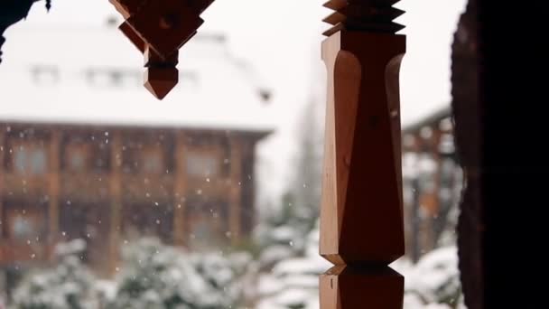冬には、背景がぼやけています。針葉樹常緑の豪雪山村の木製コテージのランドス ケープ デザイン。スキー場でログ シャレーに降る雪。凍るような冬の寒い日. — ストック動画