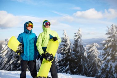İki snowboard kayak merkezi poz. Ormanı backcountry freeride için onların snowboards taşıyan ve yansıtıcı gözlük, renkli moda kıyafet giyen binici arkadaşlar. Boşaltmak alan.