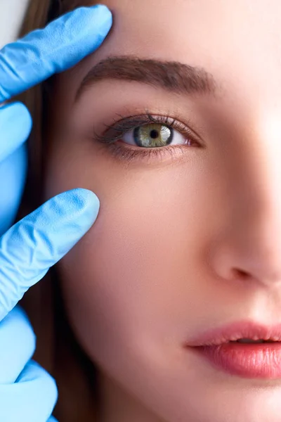 Upper eyelid reduction, double eye lid removal plastic surgery concept. Beautician doctor hands in gloves touching female face skin. Ophthalmologist or oculist checks healthy vision in green eyesight. — Stock Photo, Image