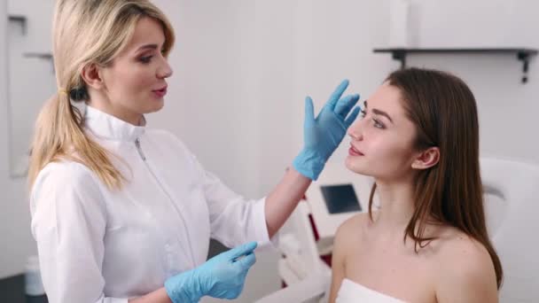 Cirujano plástico o especialista en cosmetología examina la cara de las mujeres, toca con las manos, inspecciona la piel curada después de la cirugía con resultados increíbles. Cliente y Doctor giran y miran la cámara . — Vídeos de Stock