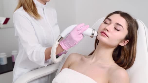 Bella bionda estetista medico facendo procedura di sollevamento rf per la donna sdraiata in un salone di bellezza. Cosmetologia hardware. Paziente che riceve un massaggio facciale elettrico. Ringiovanimento della pelle e lisciatura delle rughe . — Video Stock