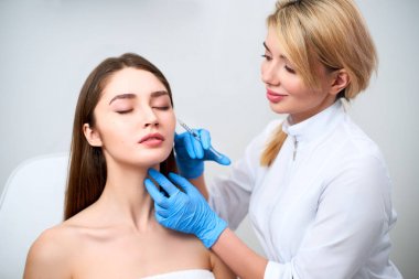 Botulinum toksin şırınga ile beautician doktor karga ayakları kaldırmak için enjeksiyon yapma. Yanak hacmi mezoterapi geliştirmek. Kozmetoloji kliniğinde anti-aging tedavisi ve yüz germe.