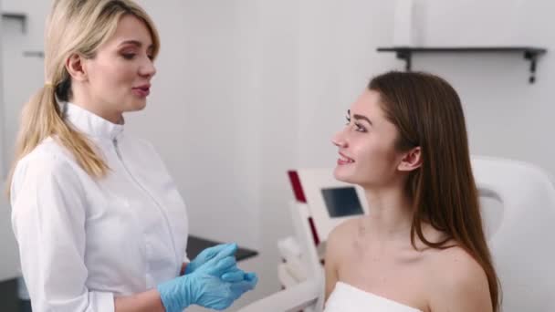 整形外科医や美容専門家は、驚くべき結果で手術後に治癒した皮膚を検査し、女性の顔、手で触れる検査を行います。クライアントと医師のターンとカメラを見て. — ストック動画