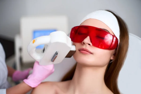 Médico esteticista haciendo rejuvenecimiento de RF láser para la cara bonita mujer joven en el salón de belleza. Elos depilación procedimiento de depilación. Tratamiento estético del acné facial cuidado de la piel. Hardware ipl cosmetología —  Fotos de Stock