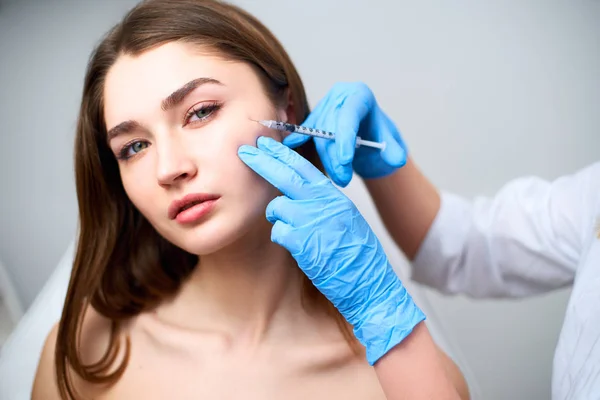 Botulinum toksin şırınga ile beautician doktor karga ayakları kaldırmak için enjeksiyon yapma. Yanak hacmi mezoterapi geliştirmek. Kozmetoloji kliniğinde anti-aging tedavisi ve yüz germe.