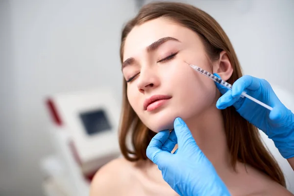 Médico esteticista con jeringa de toxina botulínica que hace la inyección para eliminar los patas de gallo. El volumen de la mejilla mejora la mesoterapia. Tratamiento antienvejecimiento y lifting facial en clínica de cosmetología . —  Fotos de Stock