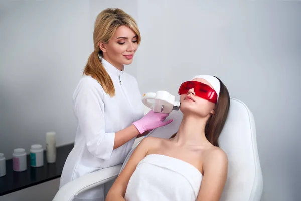 Güzellik salonunda güzel genç kadın yüz için lazer Rf gençleştirme yapıyor Güzellik doktoru. Epilasyon epilasyon işlemi. Estetik yüz akne tedavisi cilt bakımı. Donanım ipl kozmetoloji