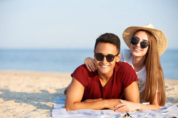 Gelukkig interracial paar jonggehuwden liggen in de zon op tropische reislocatie. Vriend en vriendin Ontspan in Spa Resort zonnebaden in de buurt van Blue Lagoon. Vrouw met tanden beugels dragen van stro hoed. — Stockfoto