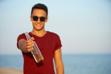 Genç yakışıklı adam gün batımında sahilde bira içiyor. Erkek, kumlu deniz kıyısında limonata ile susuzluğunu giderir. Adam ya teklif ediyor ya da soğuk içecekle birlikte cam şişe ikram ediyor. Adam elma şarabı gösteriyor..