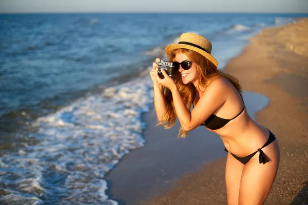 Yaz tatilinde tropikal plaj zevk Vintage Retro Film kamera ile genç otantik kadın. Saman şapka kadın seyahat fotoğrafçı denizde eğlenmek fotoğraf çekmek. Gerçek kız unretouched şekil. — Stok fotoğraf