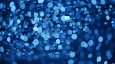 Noel için odakları kesilmiş bokeh toplarıyla soyut bir arka plan. Yeni yıl arkaplanı, parlak ampul çelenkleriyle dolu. Geceleyin parlak kış partisi ışıklarının gerçek mercek bulanıklığı.