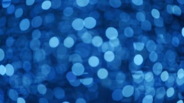 Noel için odakları kesilmiş bokeh toplarıyla soyut bir arka plan. Yeni yıl arkaplanı, parlak ampul çelenkleriyle dolu. Geceleyin parlak kış partisi ışıklarının gerçek mercek bulanıklığı.