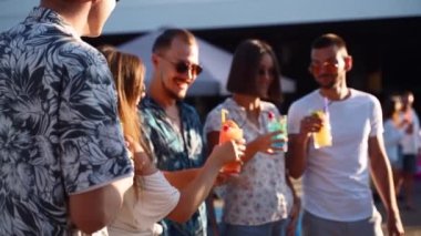 Bir grup arkadaş, havuz başında yaz partisinde bardakları tokuşturup güneşli bir günde havuz kenarında kokteyl içiyorlar. İnsanlar tropikal tatillerde lüks villada taze meyve suyu içerek kadeh kaldırıyorlar..