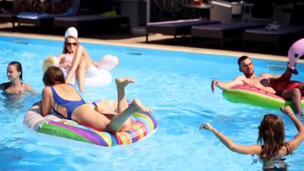 Vrienden chillen in prive villa zwembad, liggen in de zon op opblaasbare flamingo, zwaan, drijft. Jongeren ontspannen op feest in luxe resort op zonnige dag. Bikini meisjes zonnebaden. Langzame beweging. — Stockvideo