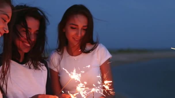 Kvinnliga vänner som går, dansar, har kul på kvällsfesten vid havet med tomtebloss i händerna. Unga tonårskvinnor festar på stranden med fyrverkerier, bengaliska ljus. Flickor i slow motion, steadycamskott. — Stockvideo