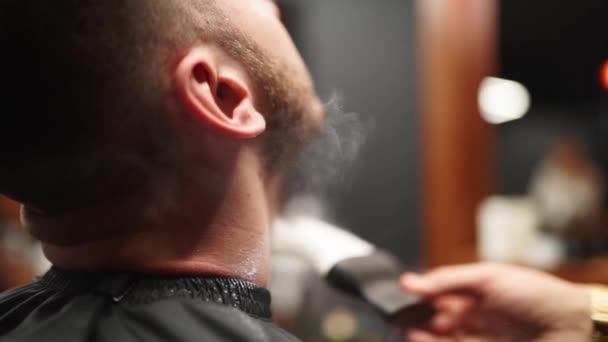 Barbeiro aplica talco em pó com escova no pescoço dos clientes depois de barbear barba e corte de cabelo no salão de cabeleireiro. Cabeleireiro limpa cliente após penteado adicionando toques finais na barbearia . — Vídeo de Stock