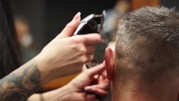 Friseurin schneidet bärtigen Männern im Friseursalon mit einem Haarschneider die Haare. Herrenfrisur und Haarschnitt im Salon. Pflege der Haare mit Trimmer. Friseur frisiert im Retro-Friseursalon. — Stockvideo