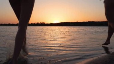 Bikinili mutlu kızlar gün batımında birbirlerine su sıçratma oyunu oynuyorlar. Bayan arkadaşlar gölde su sıçratırken eğlenirler. Genç kadın siluetleri yüzmeye gider, alacakaranlıkta havuzda yıkanırlar. Yavaşla