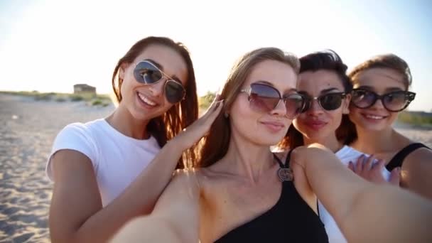 Vue panoramique de jolies femmes prennent selfie s'amuser avec des boissons sur la plage de la mer au coucher du soleil. Appel vidéo en ligne : fille regardant la caméra smartphone sur l'île tropicale, les femelles grillent des bouteilles, agitant les mains. — Video