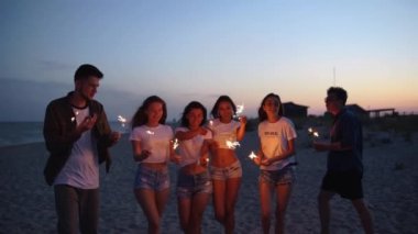 Arkadaşlar yürür, dans eder, ellerinde maytaplarla sahildeki partide eğlenirler. Genç gençler plajda havai fişekler ve bengal ışıklarıyla parti yapıyorlar. Yavaş çekim sabit kamera görüntüsü.
