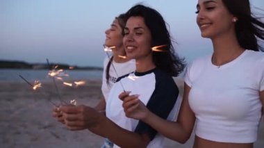 Kadın arkadaşlar yürüyor, dans ediyor, ellerinde maytaplarla sahildeki partide eğleniyorlar. Genç kızlar plajda havai fişeklerle, bengal ışıklarıyla parti yapıyorlar. Ağır çekimde kızlar, sabit kameralı çekim.