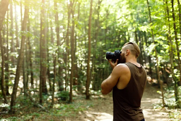 留胡子的摄影师在森林中跋涉，用相机拍照。水平形状，复制空间 — 图库照片