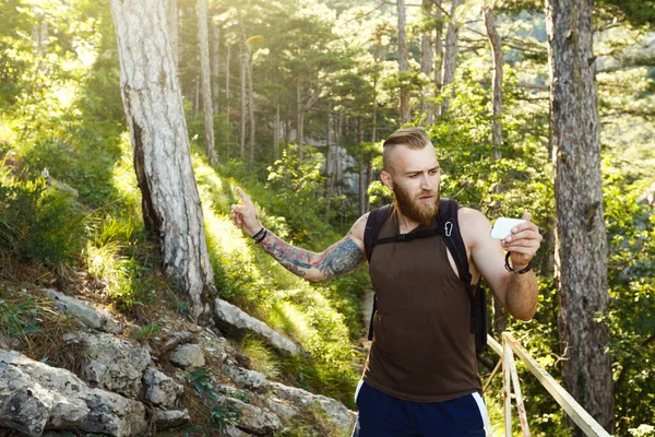 Bearded stylish hiker man using gps navigation for positioning at the mountain trail and thinks where to go. Technology concept — Stock Photo, Image