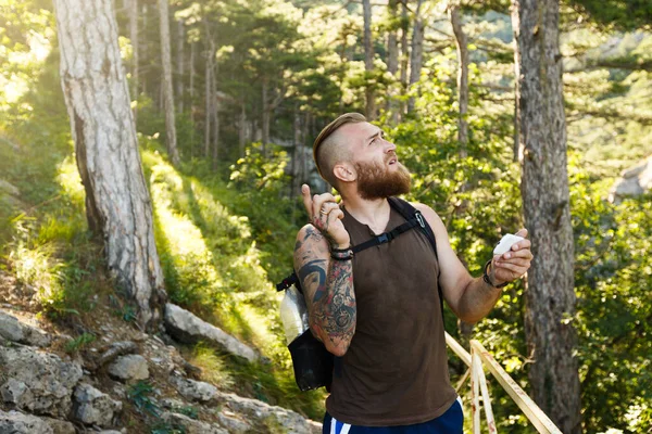 Bearded stylish hiker man using gps navigation for positioning at the mountain trail and thinks where to go. Technology concept — Stock Photo, Image