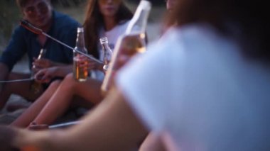 Arkadaşlar şenlik ateşinin etrafında oturur, bira şişelerini kızartır gitar çalar ve kumsalda sosis kızartırlar. Genç bir grup erkek ve kadın birlikte içki içiyorlar. Alacakaranlıkta gitar çalan adam..