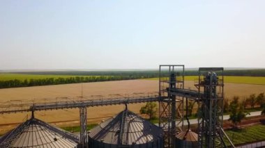 Buğday tarlasının önündeki tahıl asansörü. Quadcopter drone kamerası un ya da petrol fabrikasının üzerinde uçuyor. Çiftlik arazisinin yakınındaki silolar. Tarım teması, hasat mevsimi.