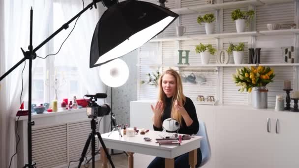 Mulher blogueira de beleza filmando tutorial de rotina de maquiagem diária na câmera. Influenciador menina loira transmissão ao vivo cílios mascasra revisão em estúdio em casa com equipamento de iluminação profissional. Trabalho Vlogger . — Vídeo de Stock