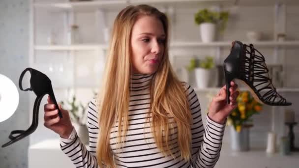 Mode bloggare kvinna i jeans och polotröja visar höga klackskor på kameran. Stylist influencer flicka visar trendiga skor filma vlog episod för hennes kanal. Opinionsledare sätter trender. — Stockvideo