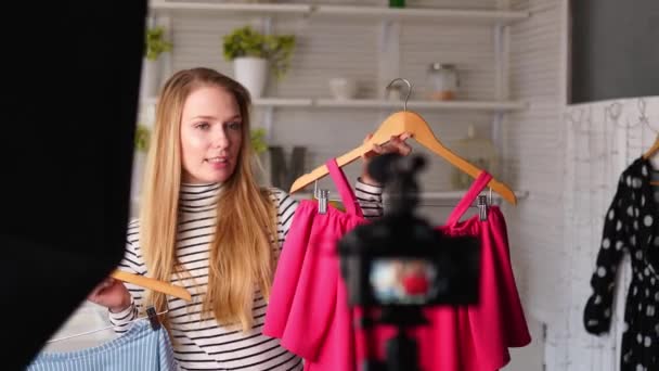 청바지와 터틀넥을 입은 패션 블로거 여성이 카메라를 통해 캐주얼 컬러 셔츠를 보여 줬다. 스타일리스트는 유행하는 옷을 입은 소녀가 채널을 위해 vlog 에피소드를 촬영하는 것을 영향을 주었다. 여론 지도자가 추세를 설정. — 비디오