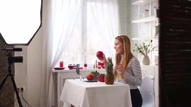 Food blogger cooking fresh vegan salad of fruits in kitchen studio, filming tutorial on camera for video channel. Female influencer holds apple, pineapple and talks about healthy eating. Fructorianism — Stock Video