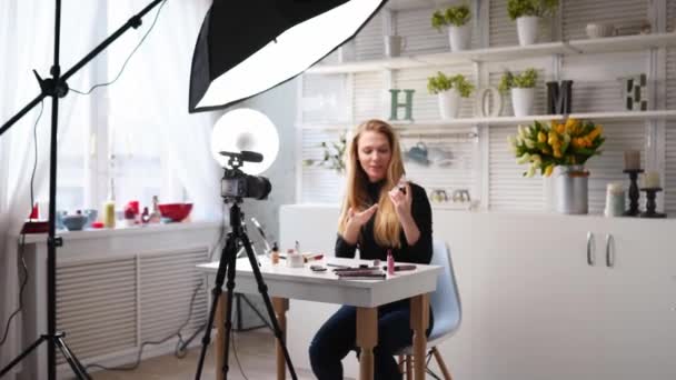 Beauty-Bloggerin filmt tägliche Make-up-Routine-Anleitung vor der Kamera. Influencer blonde Mädchen Live-Streaming Lidschatten Palette Bewertung im Heimstudio mit professioneller Beleuchtung. Vlogger-Job. — Stockvideo