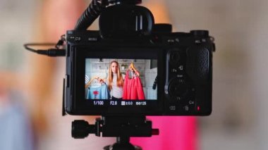 Kamera kayıtları - Moda blogcusu kadın renkli gömlekler gösteriyor. Stilist kız, kendi kanalı için son moda kıyafetleri gösteren video bloğu bölümünü çekiyor. Fikir lideri eğilimleri belirler.