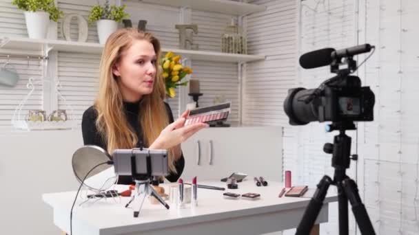 Mulher blogueira de beleza filmando tutorial de rotina de maquiagem diária perto da câmera. Influenciador menina transmissão ao vivo cosméticos revisão do produto. Vlogger fêmea recomenda paleta sombra olho, ensina em masterclass . — Vídeo de Stock