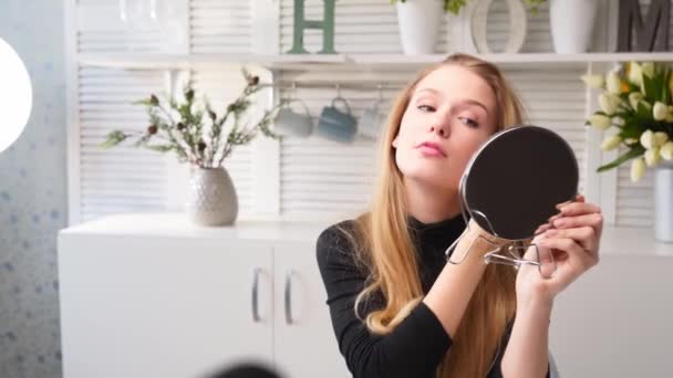 Encantadora jovem caucasiana pintando seus cílios com rímel. Beleza blogger menina filmando maquilhagem diária tutorial de rotina perto da câmera. Influenciador menina transmissão ao vivo cosméticos revisão do produto . — Vídeo de Stock