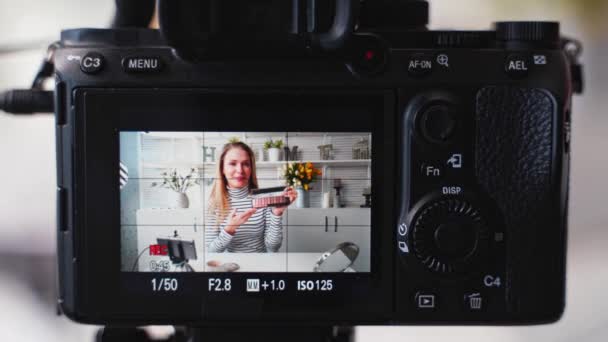 Grabación de la pantalla de la cámara - vlogger female shows eye shadow palette. Belleza blogger mujer filmando maquillaje tutorial en la cámara. Influencer chica rubia streaming en vivo cosméticos comparación de productos en el estudio — Vídeo de stock