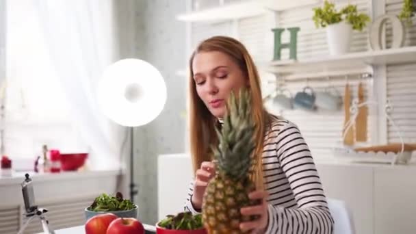Food blogger cucina fresca insalata vegana di frutta in studio di cucina, riprese tutorial sulla fotocamera per il canale video. Influencer femminile tiene mela, ananas e parla di mangiare sano. Fruttorialismo — Video Stock