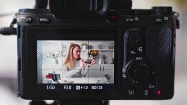 Kamera ekran kaydı. Vlogger dişisi göz farı paleti gösteriyor. Güzellik blogcusu kadın kameraya makyaj dersi veriyor. Stüdyoda canlı yayın yapan sarışın kız kozmetik ürünleri karşılaştırması