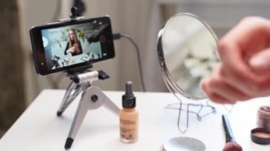 Vlogger dişisi dudaklarına ruj sürer. Güzellik blogcusu kadın günlük makyaj rutinini kameraya çekiyor. Stüdyoda canlı yayın yapan sarışın kız kozmetik ürünleri karşılaştırması